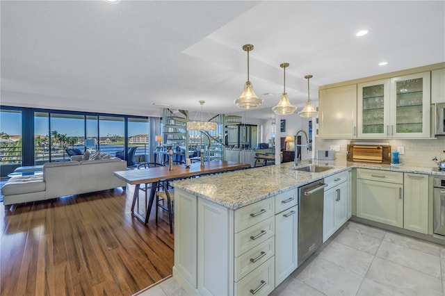 kitchen featuring light stone counters, hanging light fixtures, decorative backsplash, appliances with stainless steel finishes, and sink