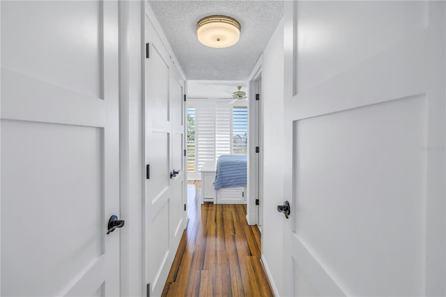 hall featuring a textured ceiling and dark hardwood / wood-style floors