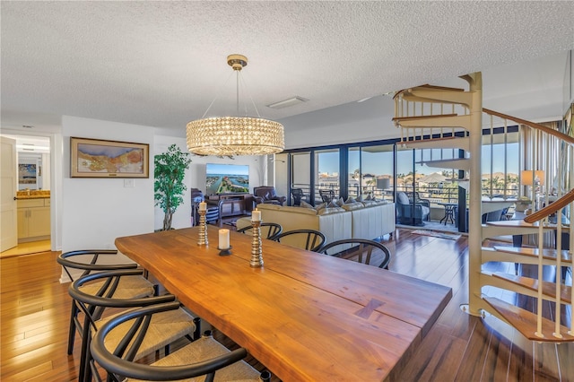 dining space with a textured ceiling, hardwood / wood-style floors, a wealth of natural light, and a notable chandelier