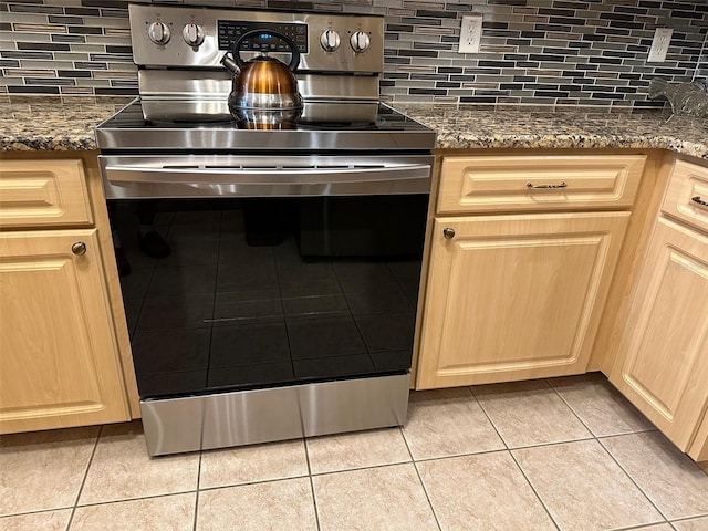 kitchen featuring tasteful backsplash, light tile patterned floors, and electric range