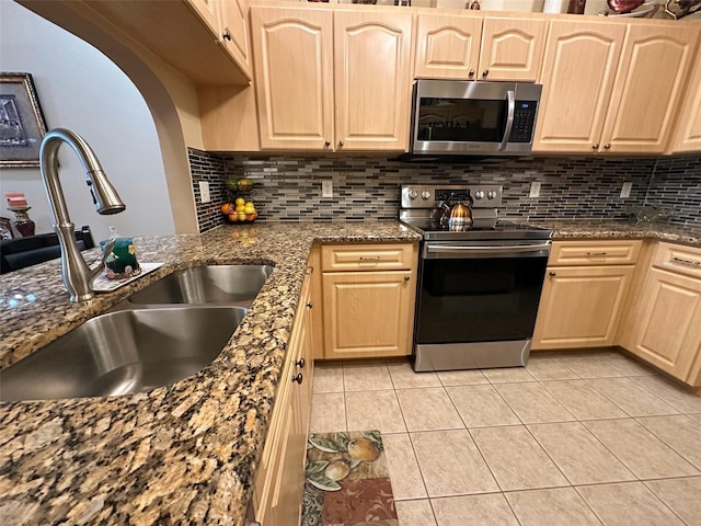 kitchen with sink, light tile patterned floors, light brown cabinets, and appliances with stainless steel finishes