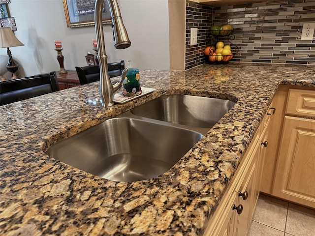 kitchen featuring tasteful backsplash, sink, dark stone counters, light tile patterned floors, and light brown cabinets