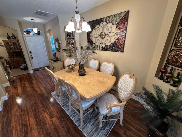 dining space featuring a notable chandelier, dark hardwood / wood-style floors, and a textured ceiling