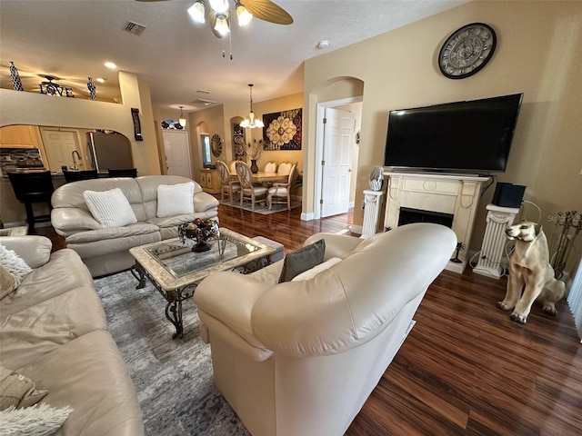 living room with ceiling fan with notable chandelier and dark wood-type flooring