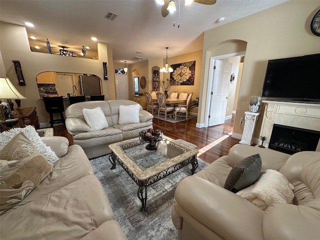 living room with dark hardwood / wood-style floors, ceiling fan with notable chandelier, and a fireplace