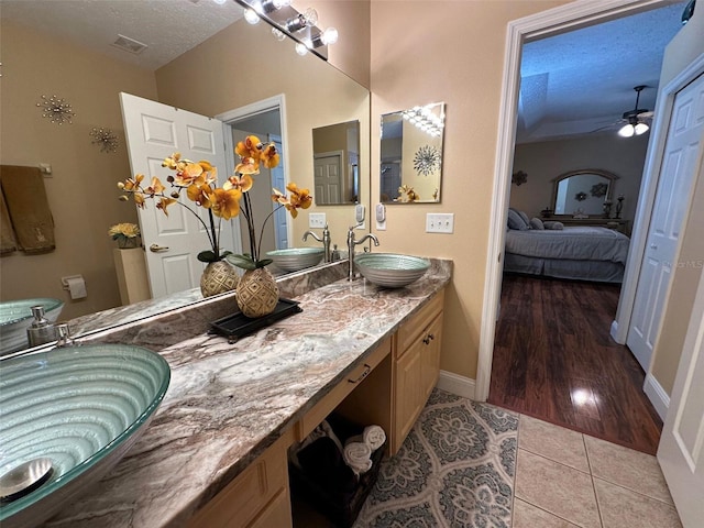 bathroom with vanity, ceiling fan, tile patterned floors, and a textured ceiling