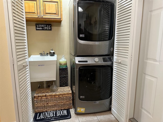 laundry area featuring stacked washer and dryer, sink, and light tile patterned floors