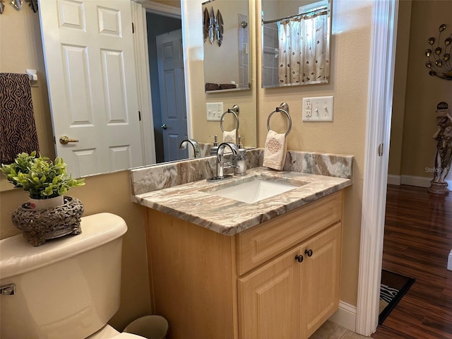 bathroom featuring vanity, wood-type flooring, and toilet