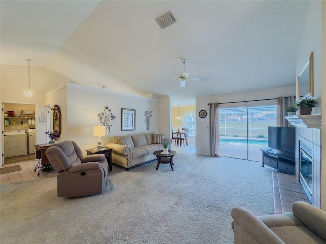 living room featuring lofted ceiling, a fireplace, separate washer and dryer, and carpet flooring