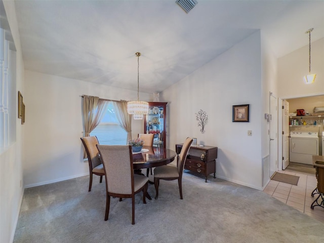 dining room featuring light carpet, independent washer and dryer, a chandelier, and lofted ceiling