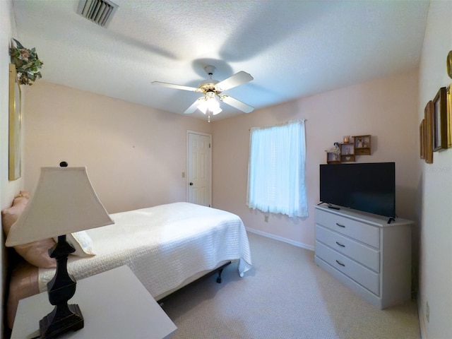 bedroom featuring ceiling fan, a textured ceiling, and light carpet