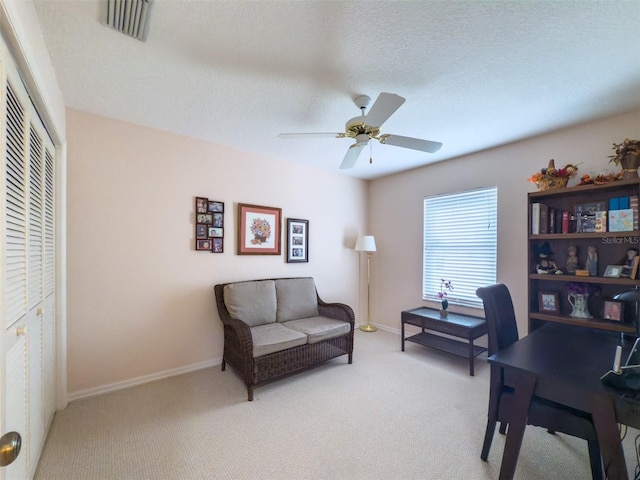 carpeted office space with ceiling fan and a textured ceiling