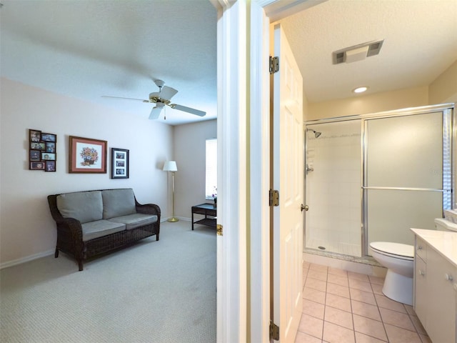 bathroom featuring toilet, ceiling fan, an enclosed shower, a textured ceiling, and vanity