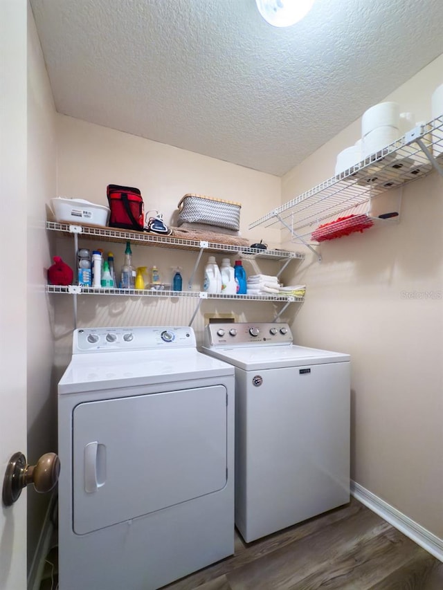 washroom featuring a textured ceiling, dark hardwood / wood-style flooring, and washing machine and clothes dryer