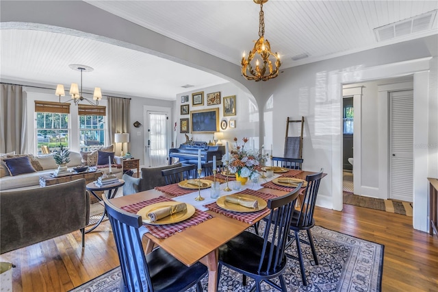 dining space with ornamental molding, dark wood-type flooring, and a notable chandelier