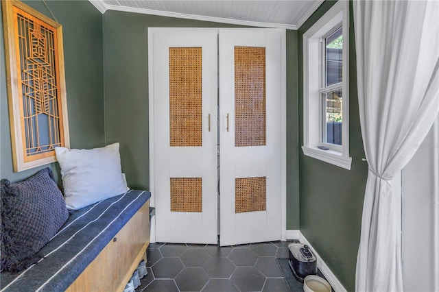 doorway featuring lofted ceiling, dark tile patterned flooring, and crown molding