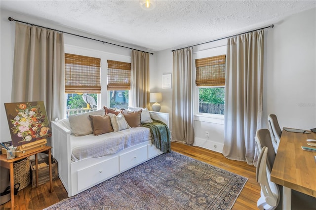 bedroom featuring multiple windows, wood-type flooring, and a textured ceiling