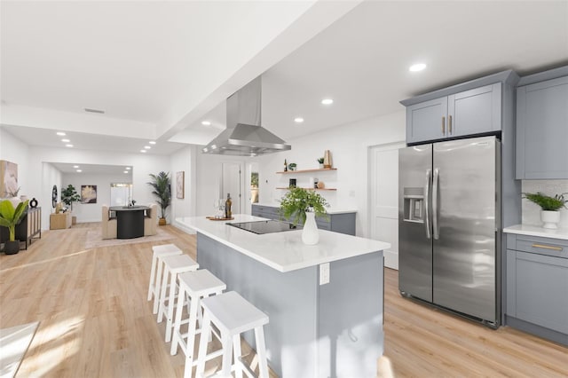 kitchen with gray cabinets, stainless steel fridge with ice dispenser, and wall chimney exhaust hood