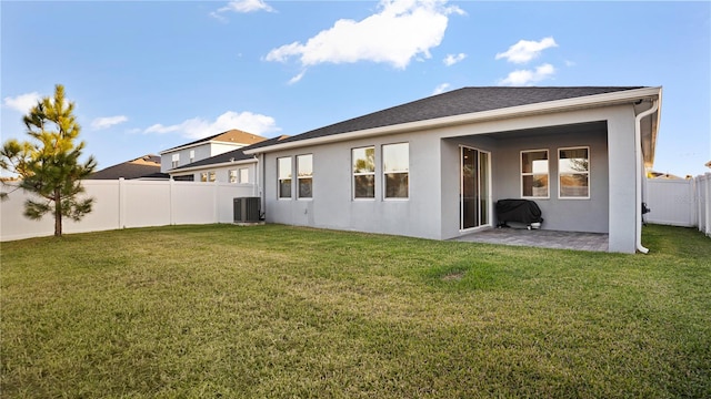 back of property with a lawn, a patio area, and central AC unit