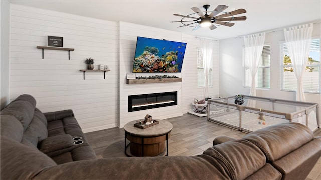 living room with a large fireplace and ceiling fan