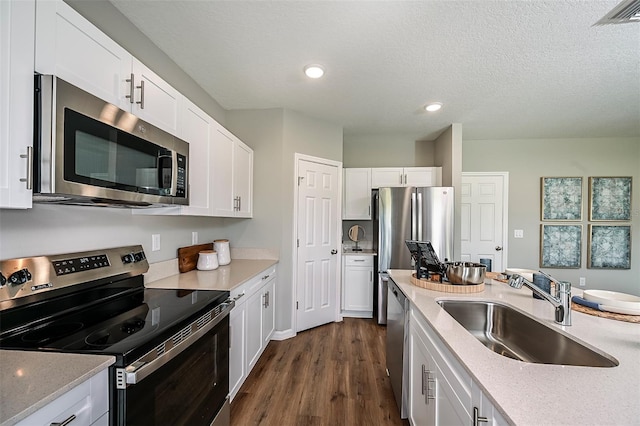 kitchen with white cabinets, sink, a textured ceiling, dark hardwood / wood-style flooring, and stainless steel appliances