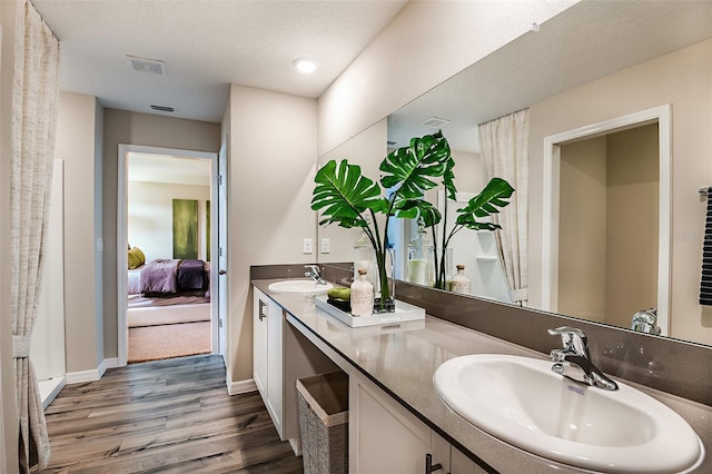 bathroom with a textured ceiling, vanity, and hardwood / wood-style flooring