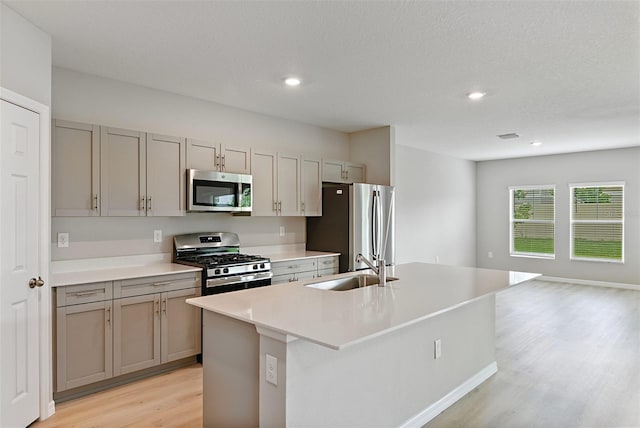 kitchen with sink, a center island with sink, light hardwood / wood-style floors, and appliances with stainless steel finishes