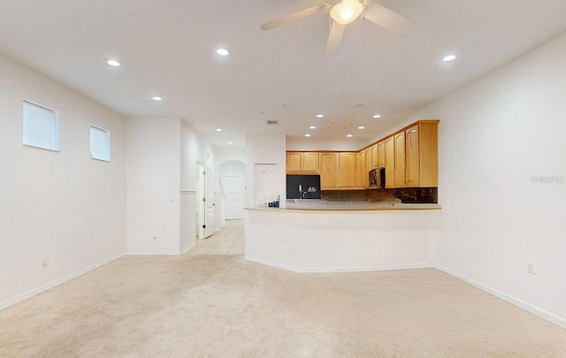 unfurnished living room featuring light carpet and ceiling fan