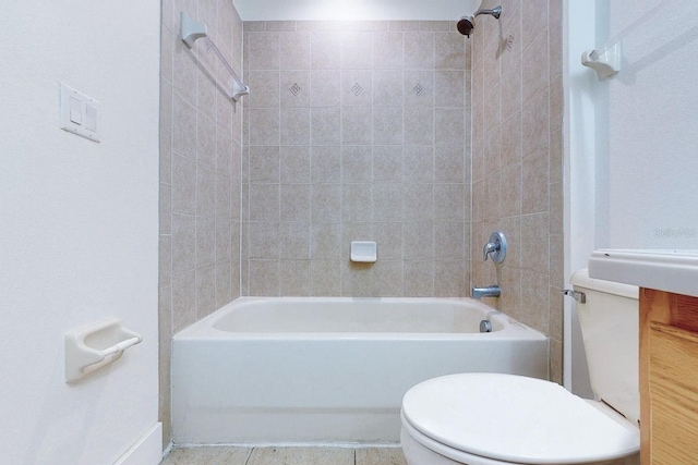 bathroom featuring tile patterned flooring, tiled shower / bath, and toilet