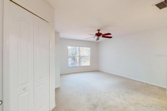 spare room featuring ceiling fan and light carpet