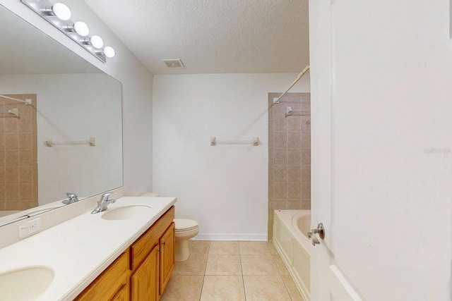 full bathroom with tile patterned floors, a textured ceiling, vanity, toilet, and tiled shower / bath