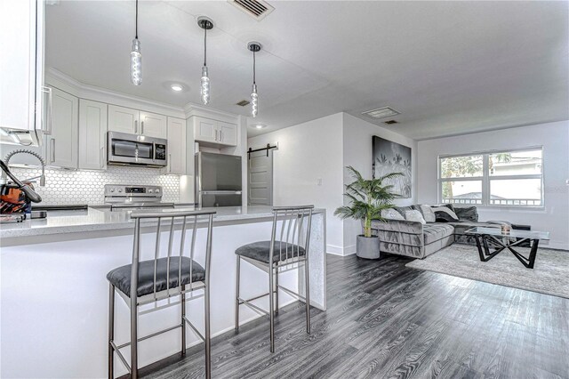 kitchen featuring a barn door, visible vents, appliances with stainless steel finishes, light countertops, and backsplash