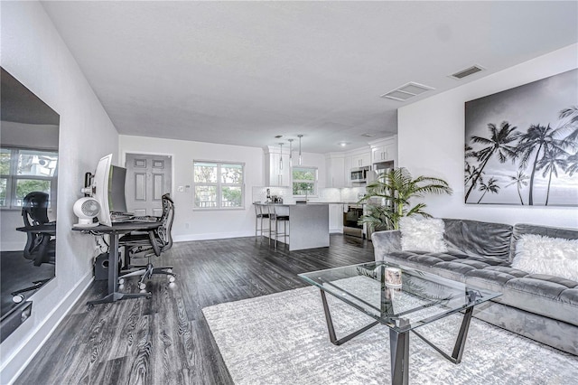 living room with dark wood finished floors, visible vents, and baseboards