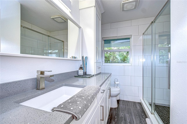 full bath with toilet, wood finished floors, vanity, tile walls, and a shower stall