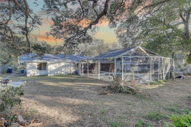 back house at dusk featuring a lanai