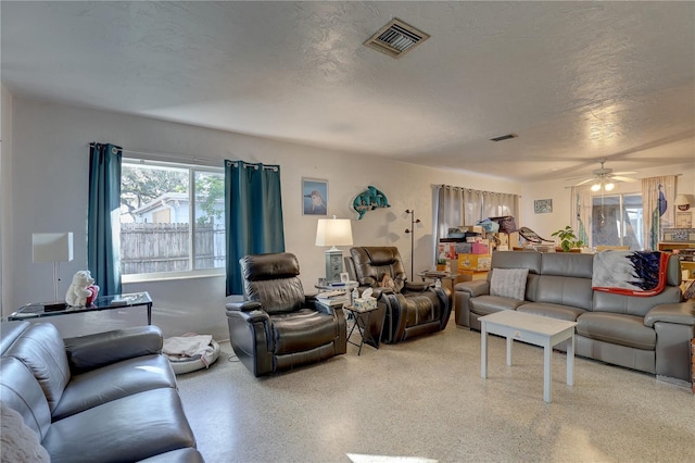 living room featuring ceiling fan and a textured ceiling