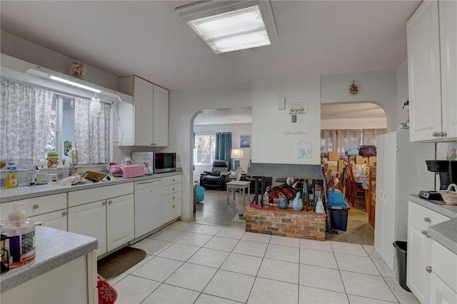 kitchen featuring white cabinetry, dishwasher, light tile patterned floors, and sink