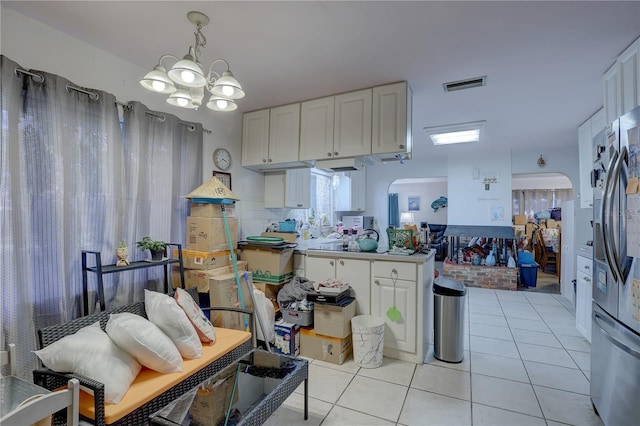 kitchen featuring pendant lighting, white cabinets, stainless steel refrigerator with ice dispenser, light tile patterned floors, and a notable chandelier