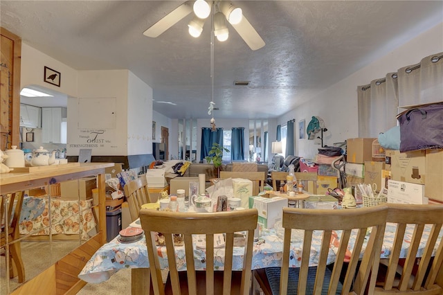 carpeted dining room featuring ceiling fan and a textured ceiling