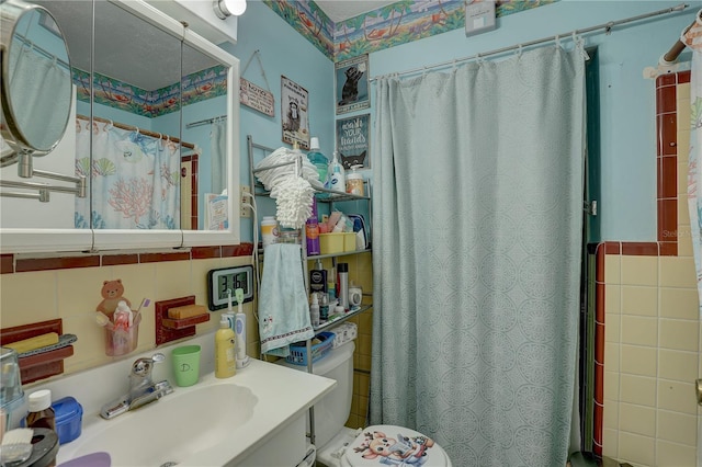 bathroom with vanity, curtained shower, toilet, and tile walls