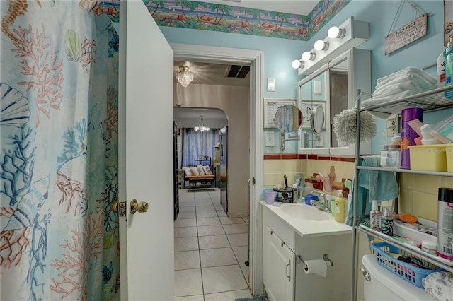 bathroom featuring tile patterned floors, vanity, a notable chandelier, and toilet