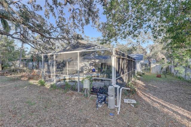 back of house featuring glass enclosure and a storage shed