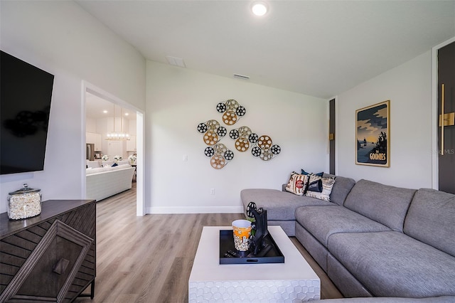 living room with light hardwood / wood-style floors and a notable chandelier