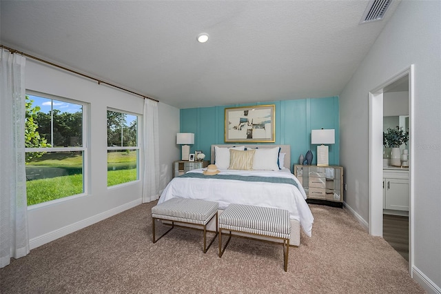 bedroom with carpet, a textured ceiling, and ensuite bath