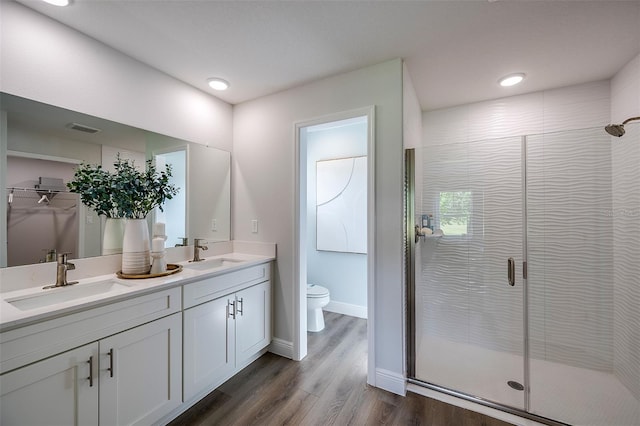 bathroom with vanity, toilet, a shower with door, and wood-type flooring