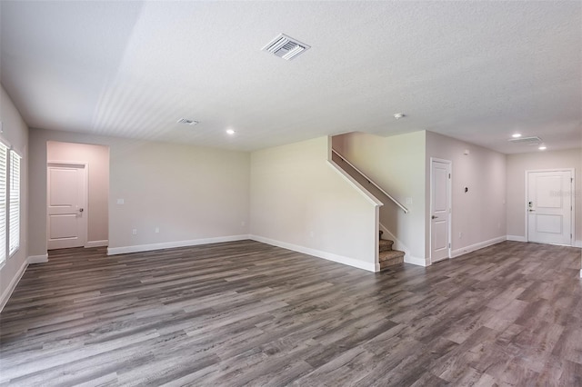 unfurnished living room with a textured ceiling and dark hardwood / wood-style floors