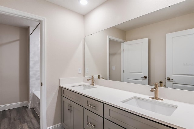 bathroom with a bathing tub, vanity, and wood-type flooring