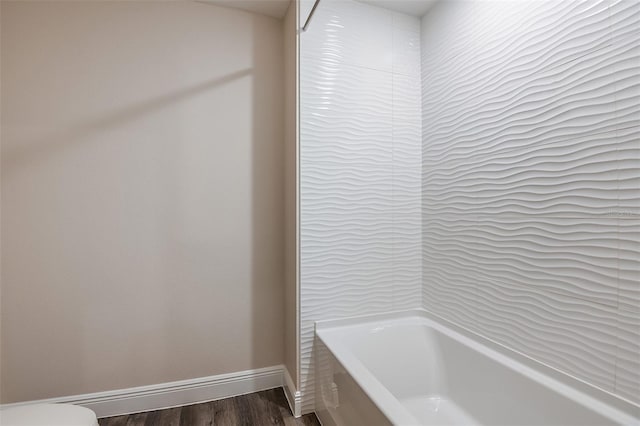 bathroom featuring hardwood / wood-style floors, toilet, and a bath