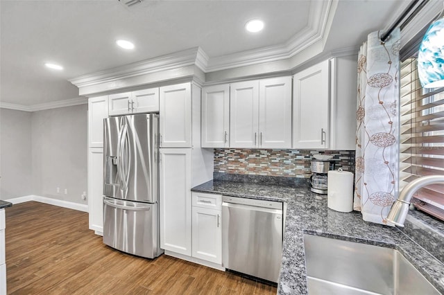 kitchen with sink, tasteful backsplash, dark stone counters, white cabinets, and appliances with stainless steel finishes