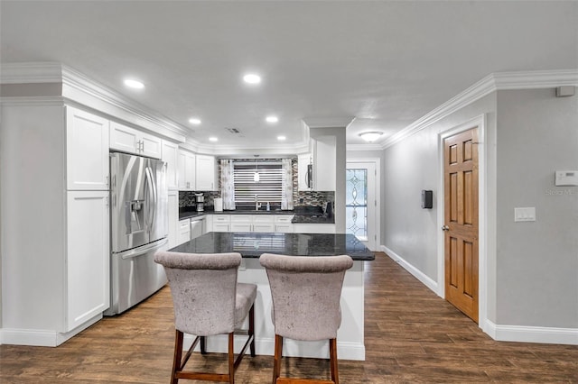 kitchen featuring backsplash, a kitchen breakfast bar, stainless steel refrigerator with ice dispenser, a kitchen island, and white cabinetry